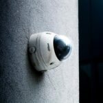 Close-up view of a dome security camera mounted on a concrete wall for surveillance.
